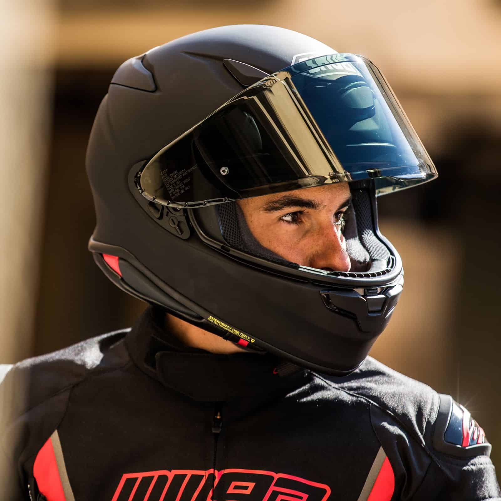 Rider wearing a matte black full-face helmet with a tinted visor, looking to the side