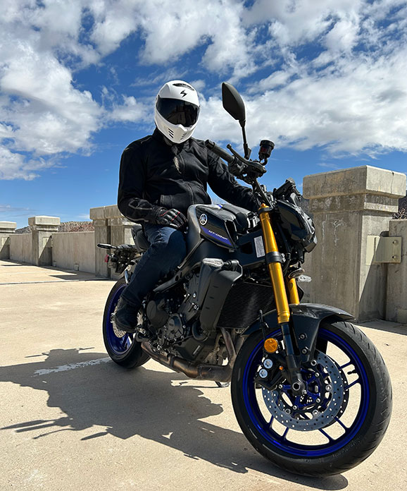 Rider wearing Scorpion EXO-Covert FX helmet on a naked bike under a blue sky