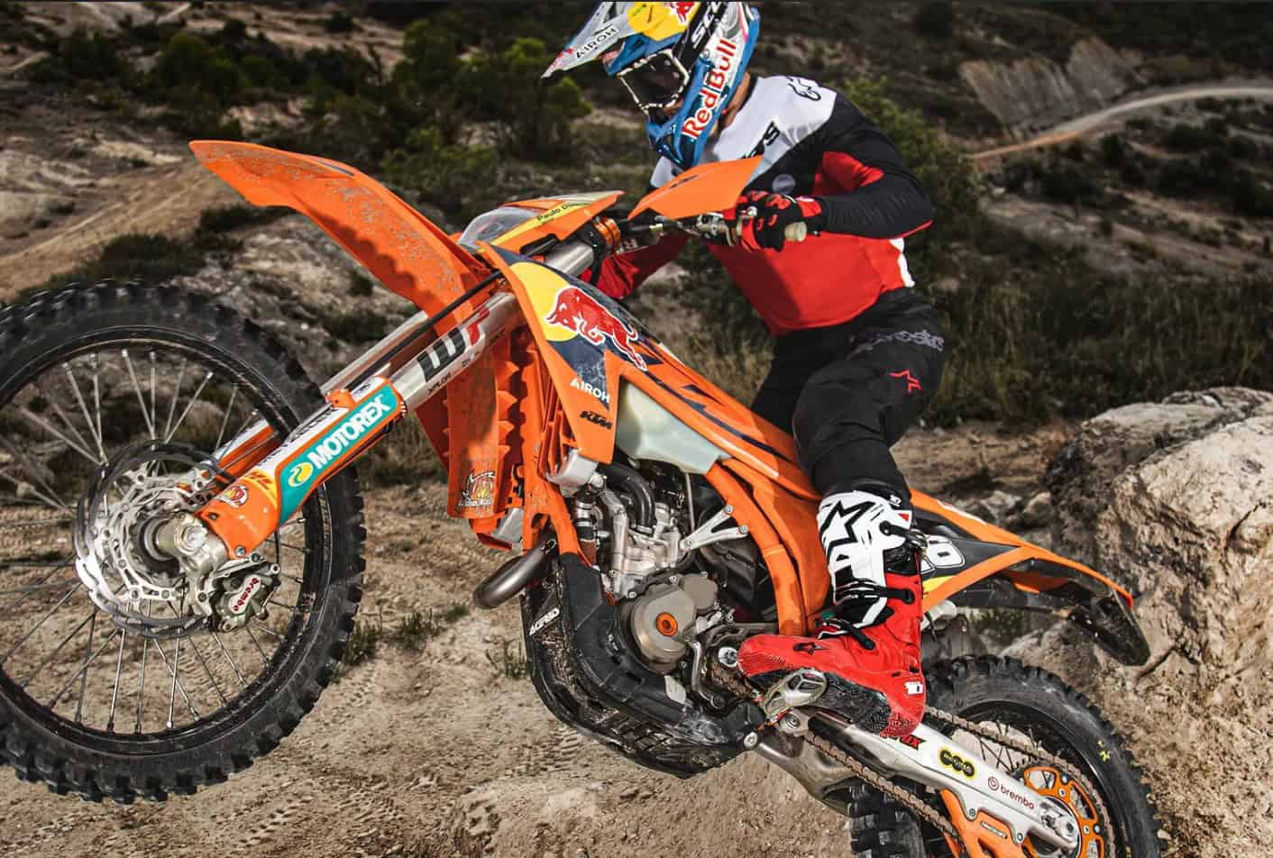 Rider wearing enduro boots climbing rocky trail on dirt bike