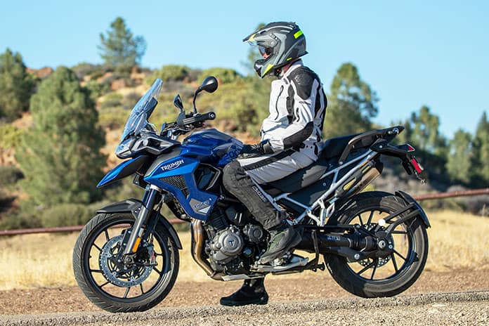 Motorcyclist wearing Sedici adventure gear seated on a Triumph ADV bike in a dry, open landscape
