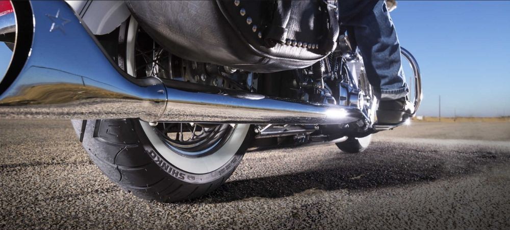 Close-up of a cruiser motorcycle’s rear tire with whitewall detail on an asphalt road