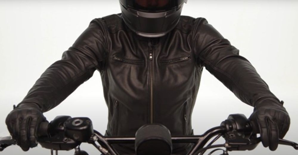 Motorcyclist wearing a black Street & Steel leather jacket and gloves, seated on a cruiser-style motorcycle