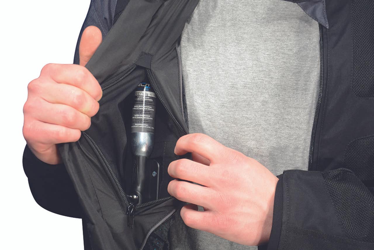 Close-up of a rider revealing the gas canister inside a motorcycle airbag vest for replacement or servicing.