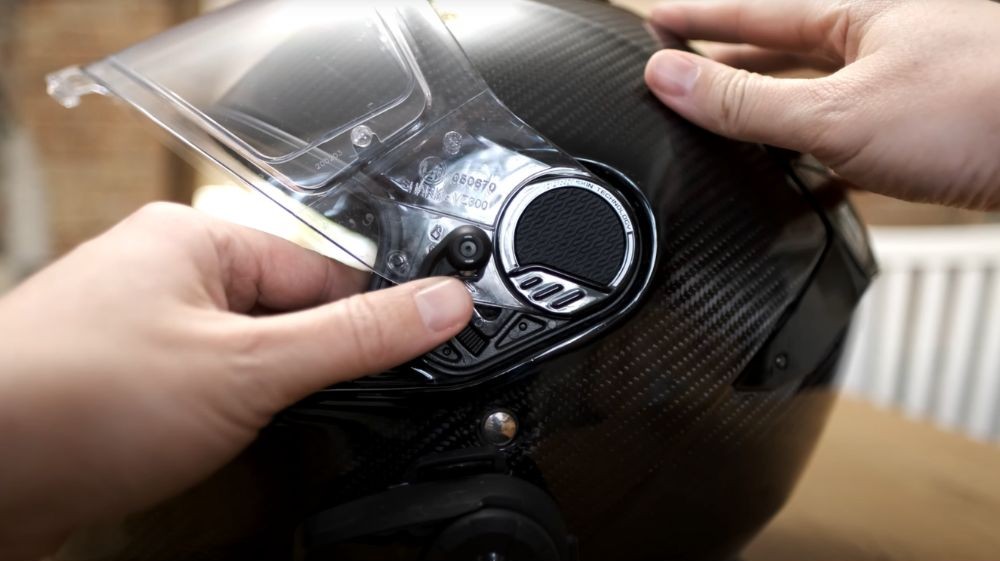 Hands turning the visor release dial on the Shark Spartan GT Carbon helmet