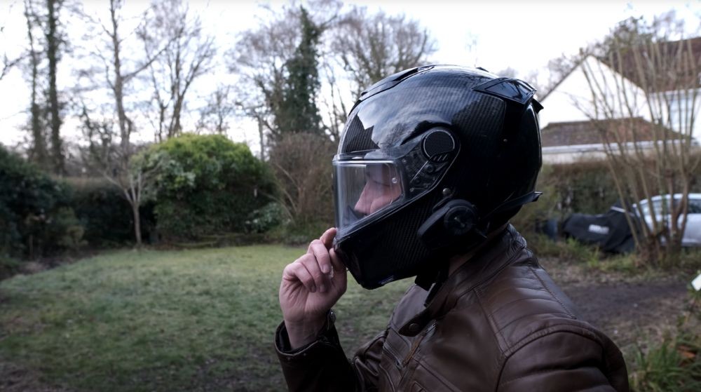 Rider wearing the Shark Spartan GT Carbon helmet pressing the visor button outdoors