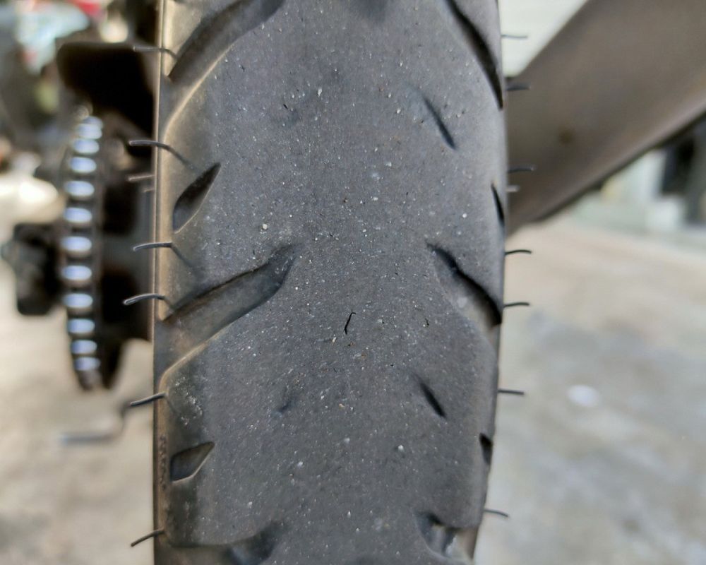 Close-up of a worn motorcycle tire showing tread wear and flat center from highway use.