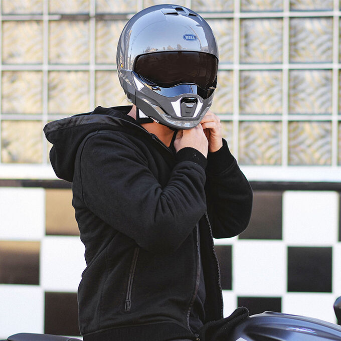 Rider adjusting chin strap on Bell Broozer helmet in urban setting