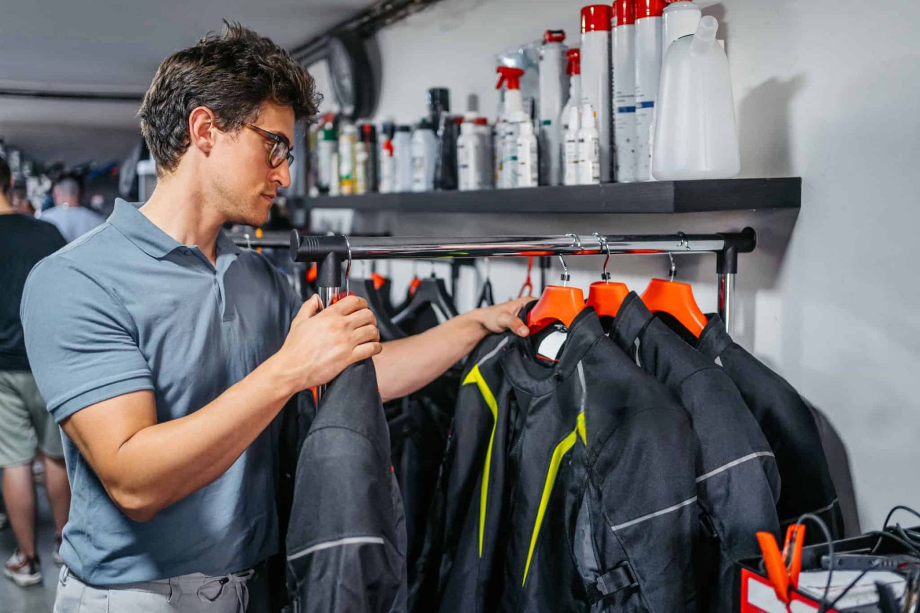Man shopping for motorcycle jackets, inspecting different styles and features in a gear store