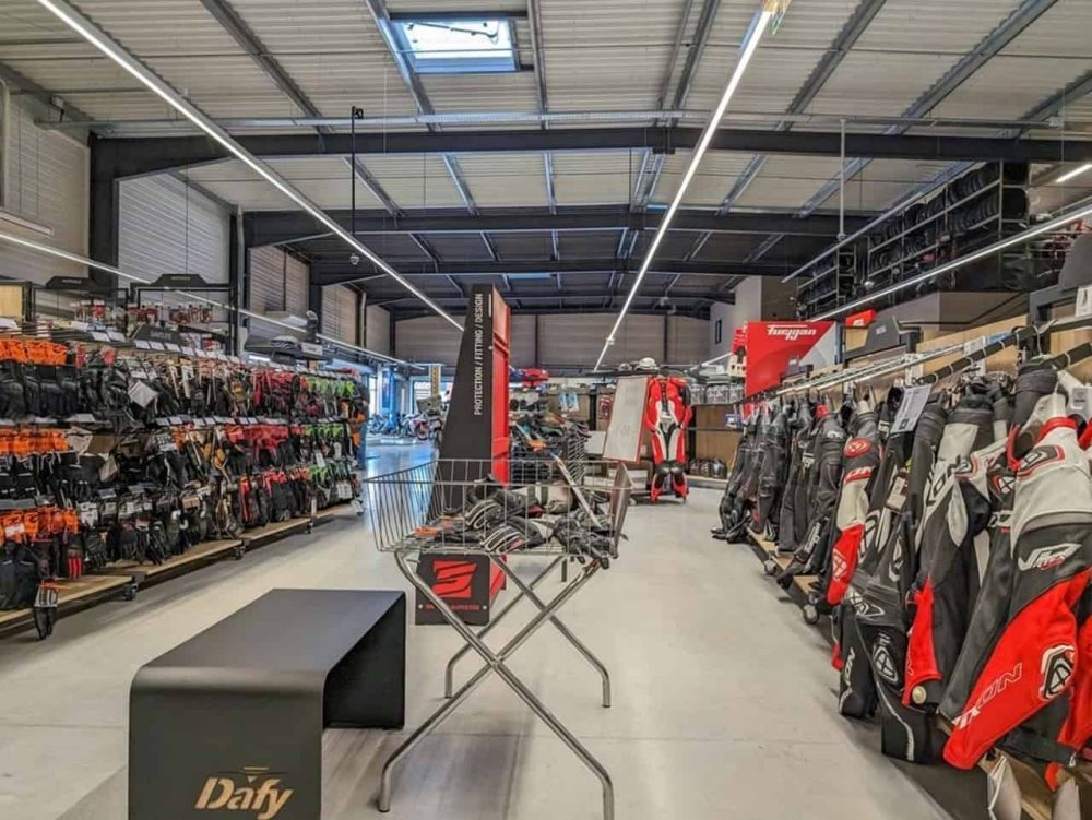 Interior of a motorcycle gear store with gloves, jackets, and protective riding suits on display, ready for summer gear shopping