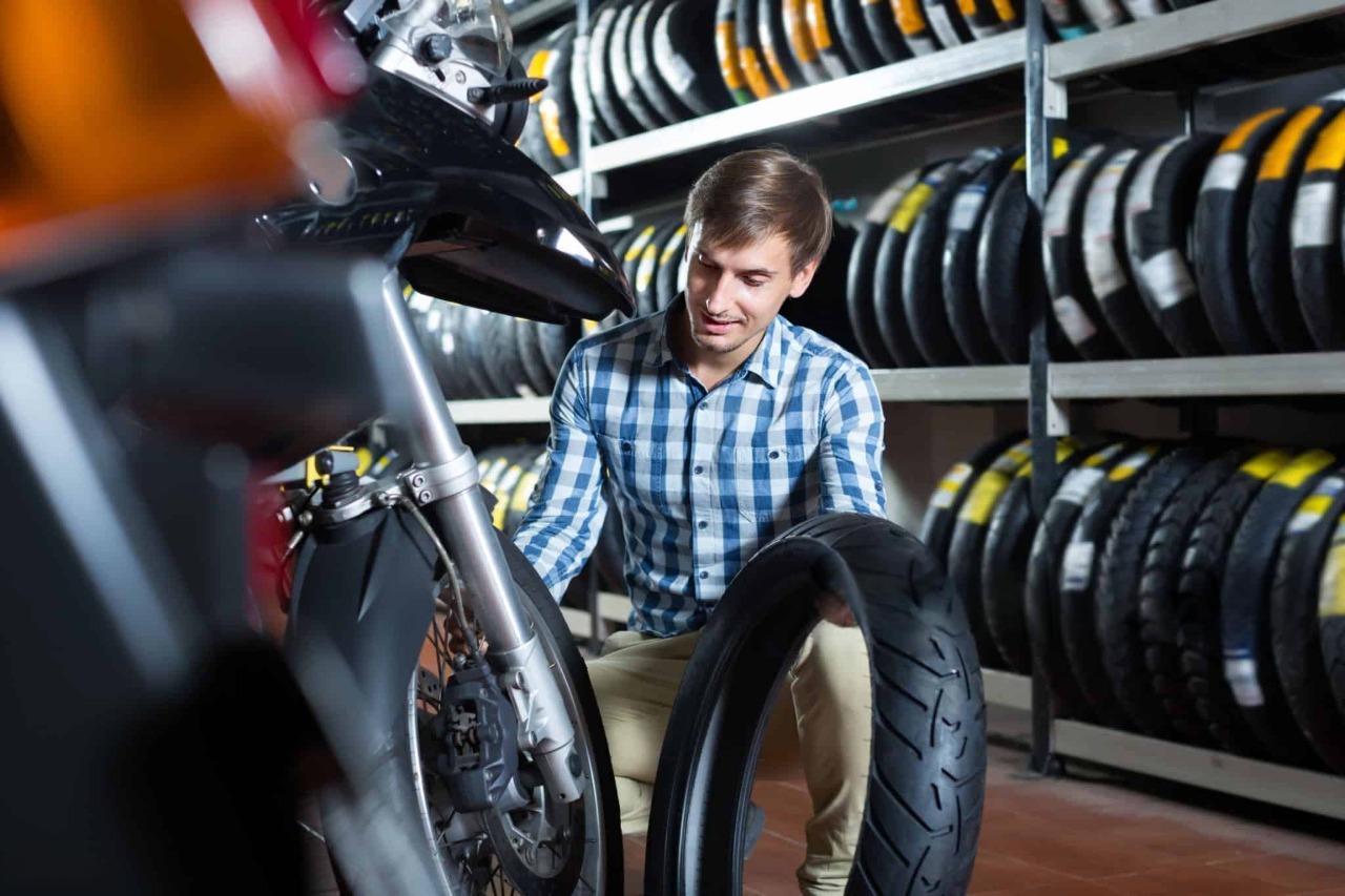 Man choosing a motorcycle tire in a tire shop surrounded by various motorcycle tires on shelves