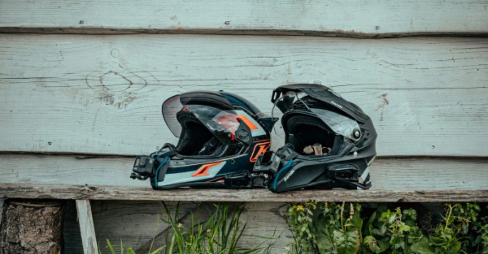 Two adventure helmets equipped with different comm systems, highlighting Cardo and Sena Mesh pairing limitations