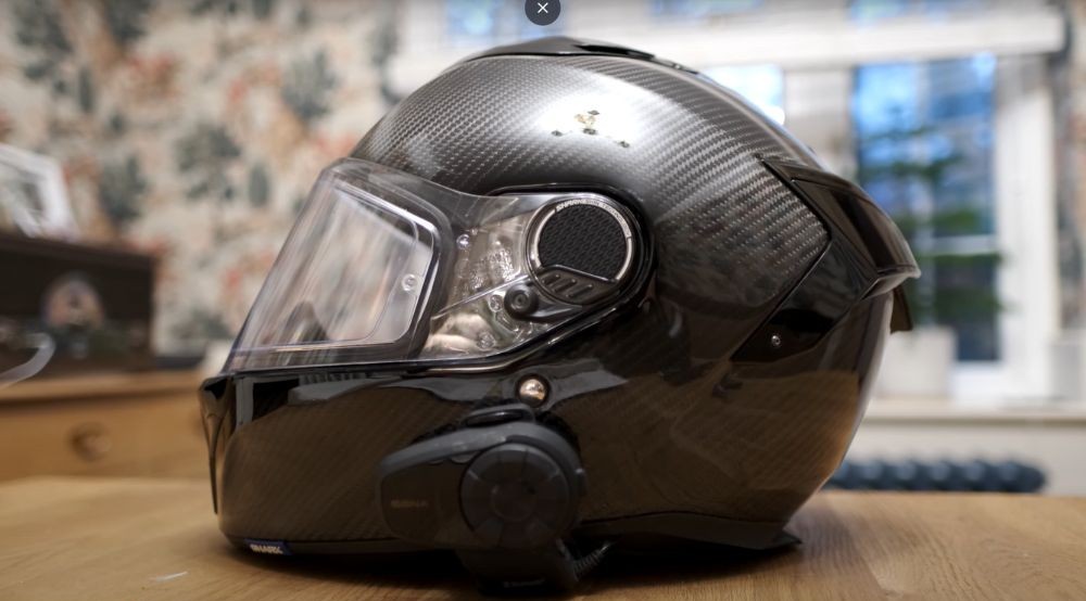 Side profile of the Shark Spartan GT Carbon helmet showing its gloss carbon finish and intercom unit