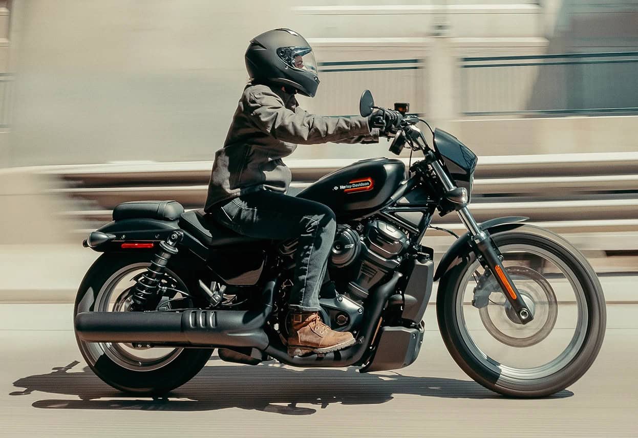 Rider in full-face helmet cruising on a black Harley-style motorcycle in motion