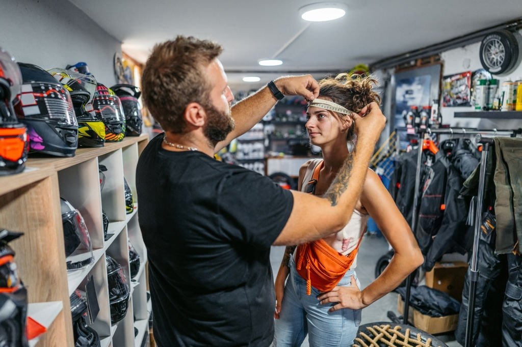 Helmet fitter measures customer’s head in motorcycle gear shop