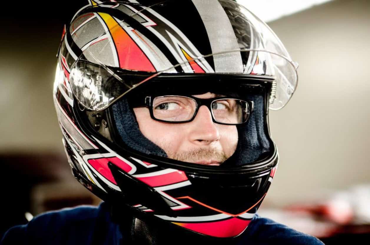 Man wearing eyeglasses under a full-face motorcycle helmet.