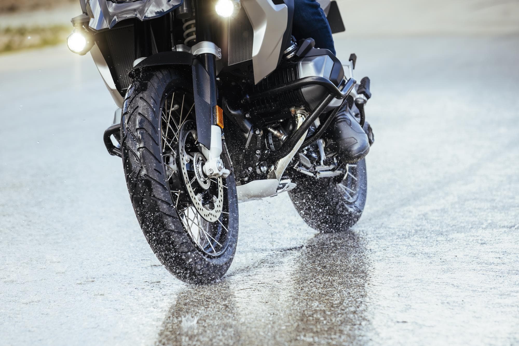 Motorcycle tire splashing on wet road during adventure riding