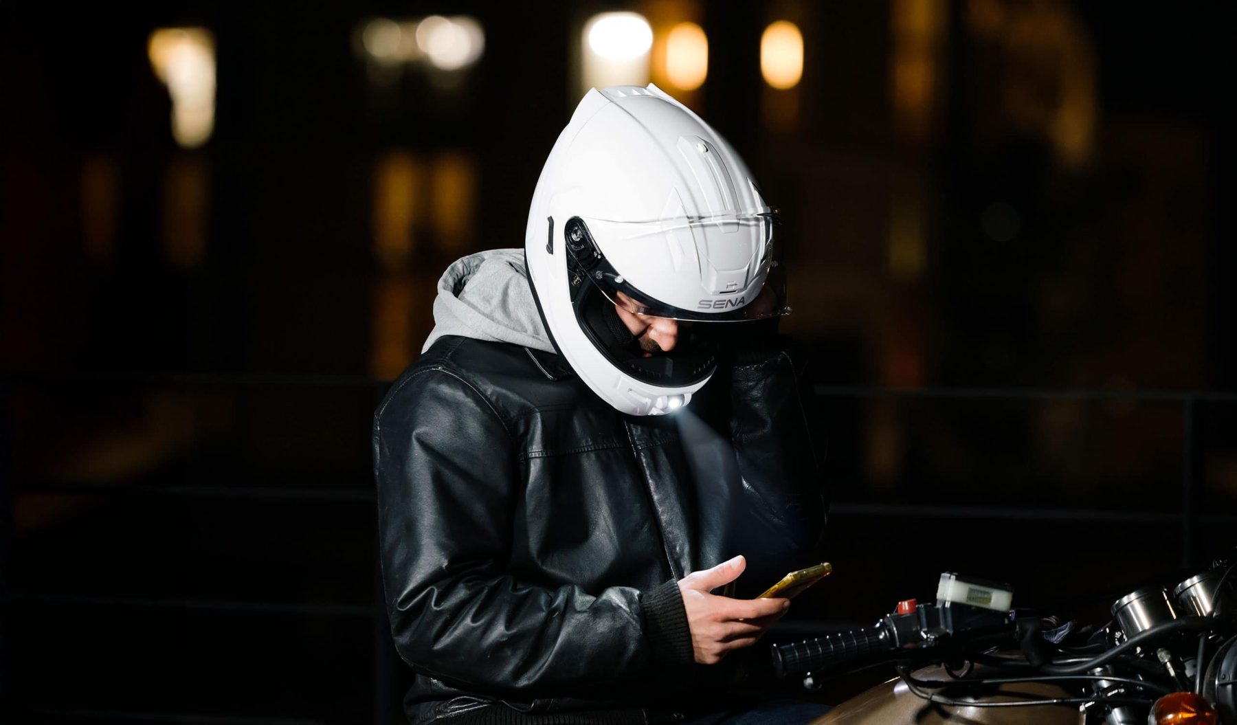 Rider using integrated comms system inside a Sena full-face helmet at night