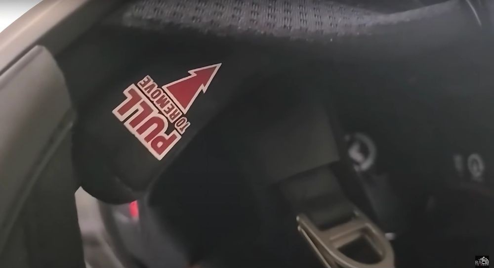 Close-up of helmet cheek pad with "Pull to Remove" emergency tag