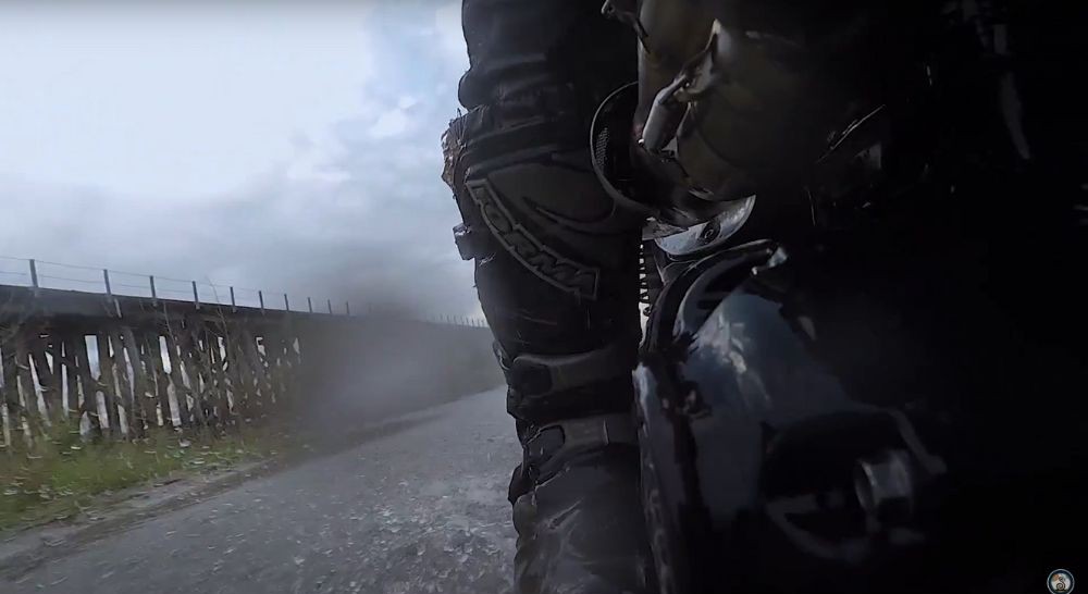 Rider’s boot close-up while riding through wet road conditions, rain splashing off the pavement
