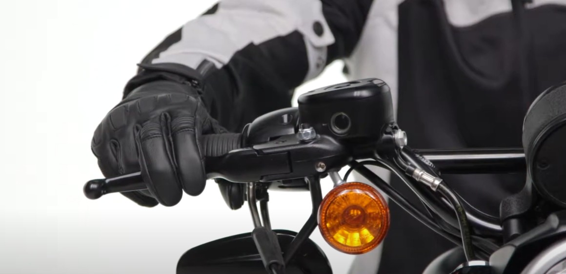 Motorcyclist gripping handlebar wearing REAX Tasker leather gloves, designed for durability, comfort, and all-around protection.