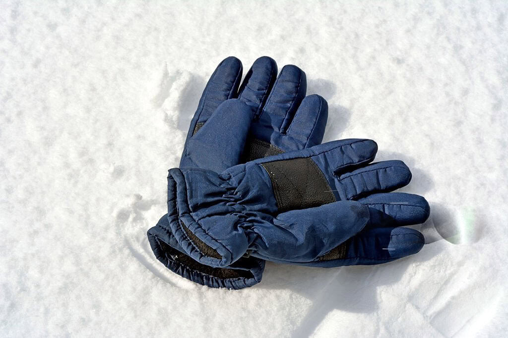 Blue ski gloves resting on snow, unsuitable for motorcycle protection