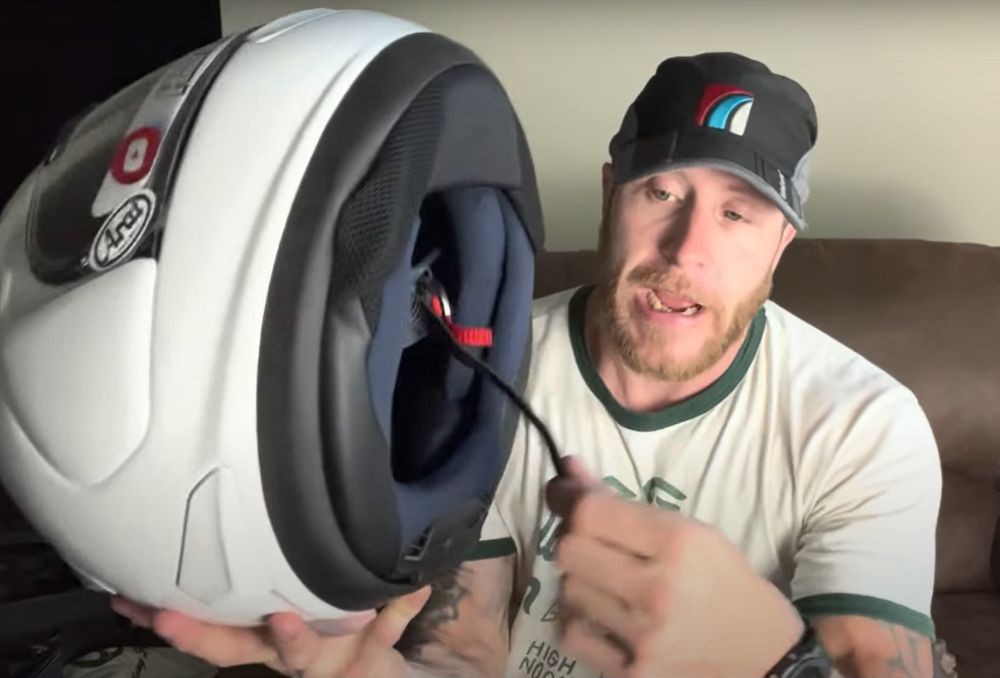 Rider demonstrating how to secure the chin strap on an Arai Corsair X helmet using the D-ring system