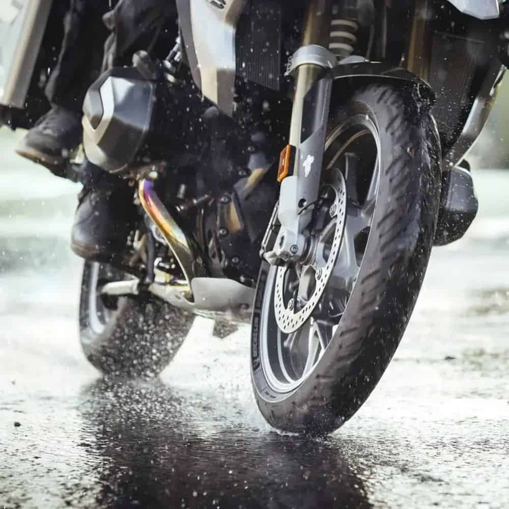 Close-up of motorcycle tire splashing water on wet pavement during a ride
