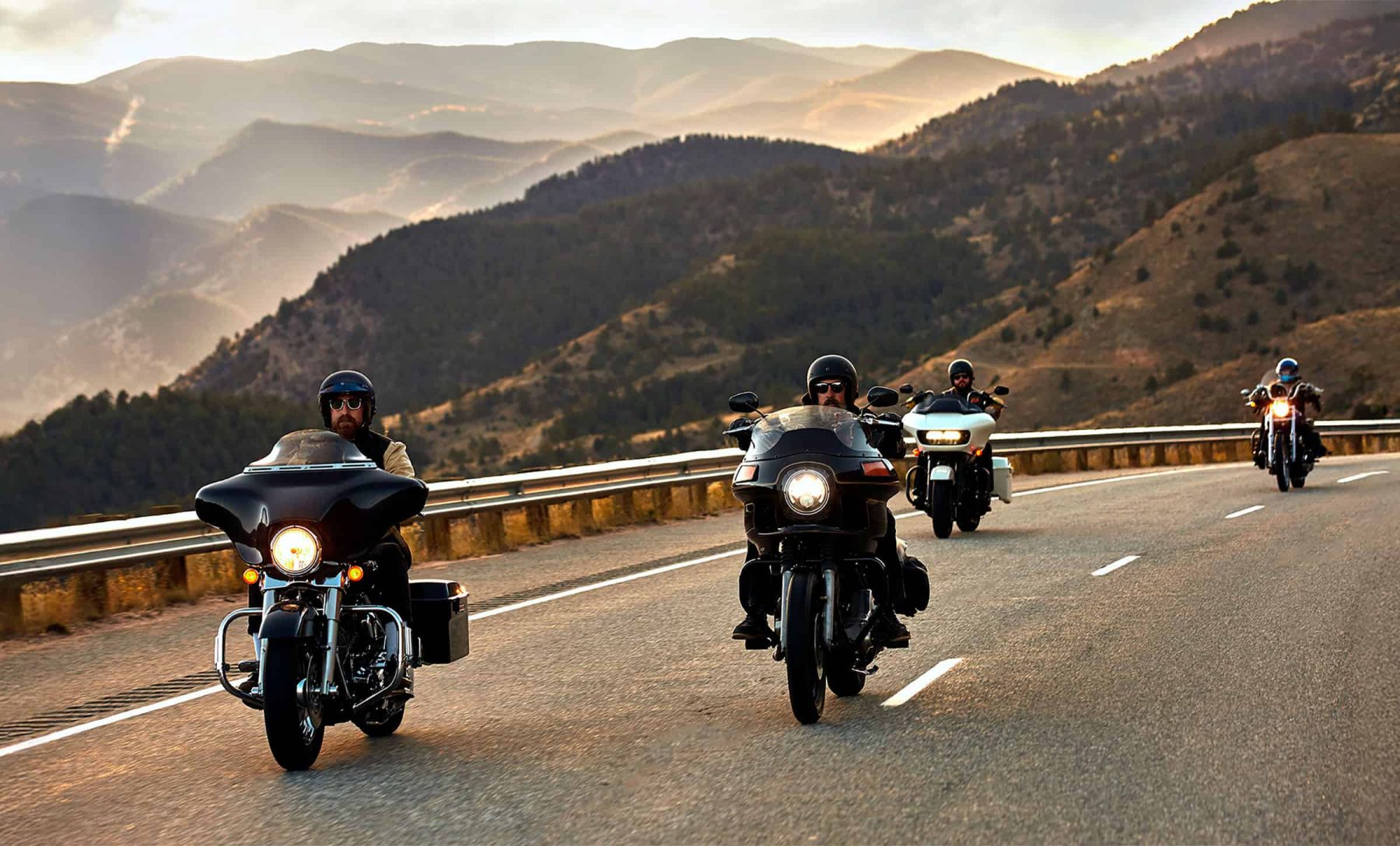 Group of motorcyclists riding through mountain roads at sunset