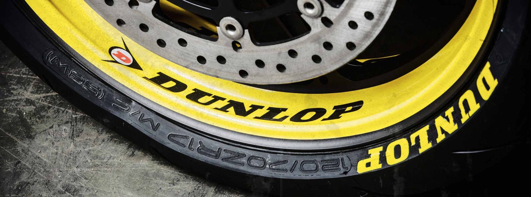 Close-up of a Dunlop motorcycle tire showing size, speed rating, and date code on the sidewall.