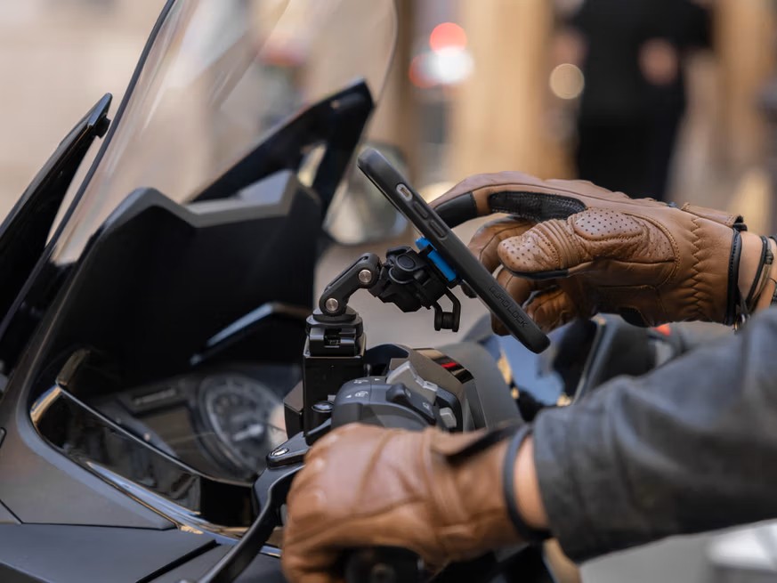 Rider using Quad Lock phone mount on motorcycle with gloves