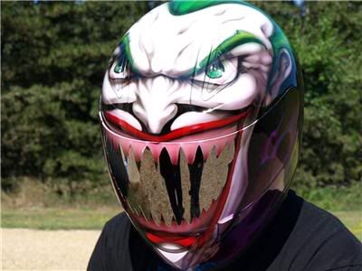 Motorcycle helmet with a full-face custom paint job resembling the Joker's face, featuring green hair, sinister eyes, and sharp teeth.