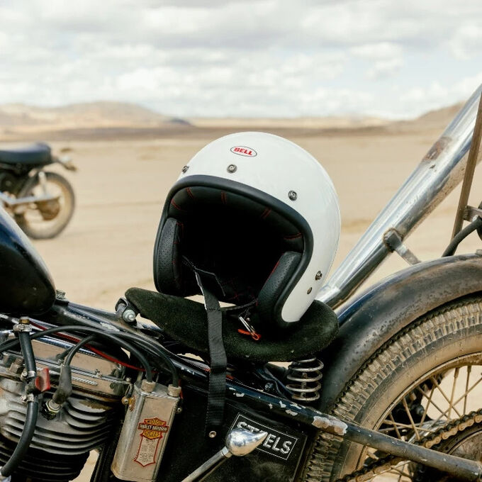 White Bell Custom 500 Edge Helmet resting on a vintage motorcycle in the desert