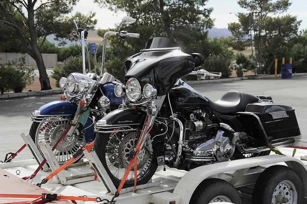 Two large touring motorcycles secured with ratchet straps on a trailer using soft loops and coated hooks