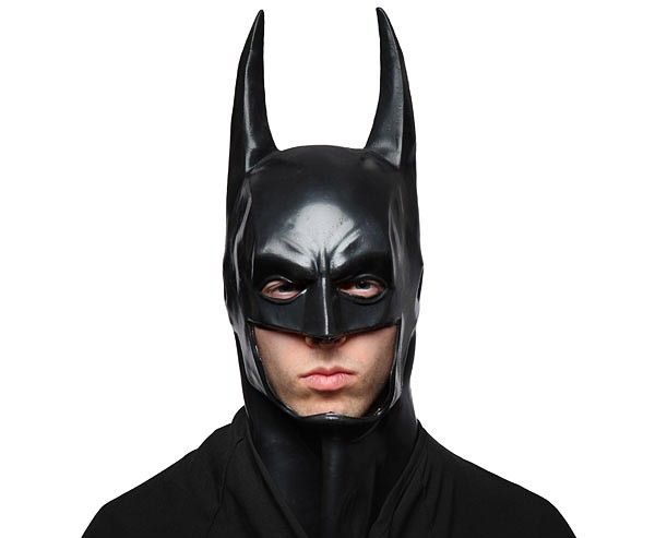 Person wearing a Batman costume cowl made of rubber or latex, styled after the Dark Knight, with exposed face and no real helmet structure.