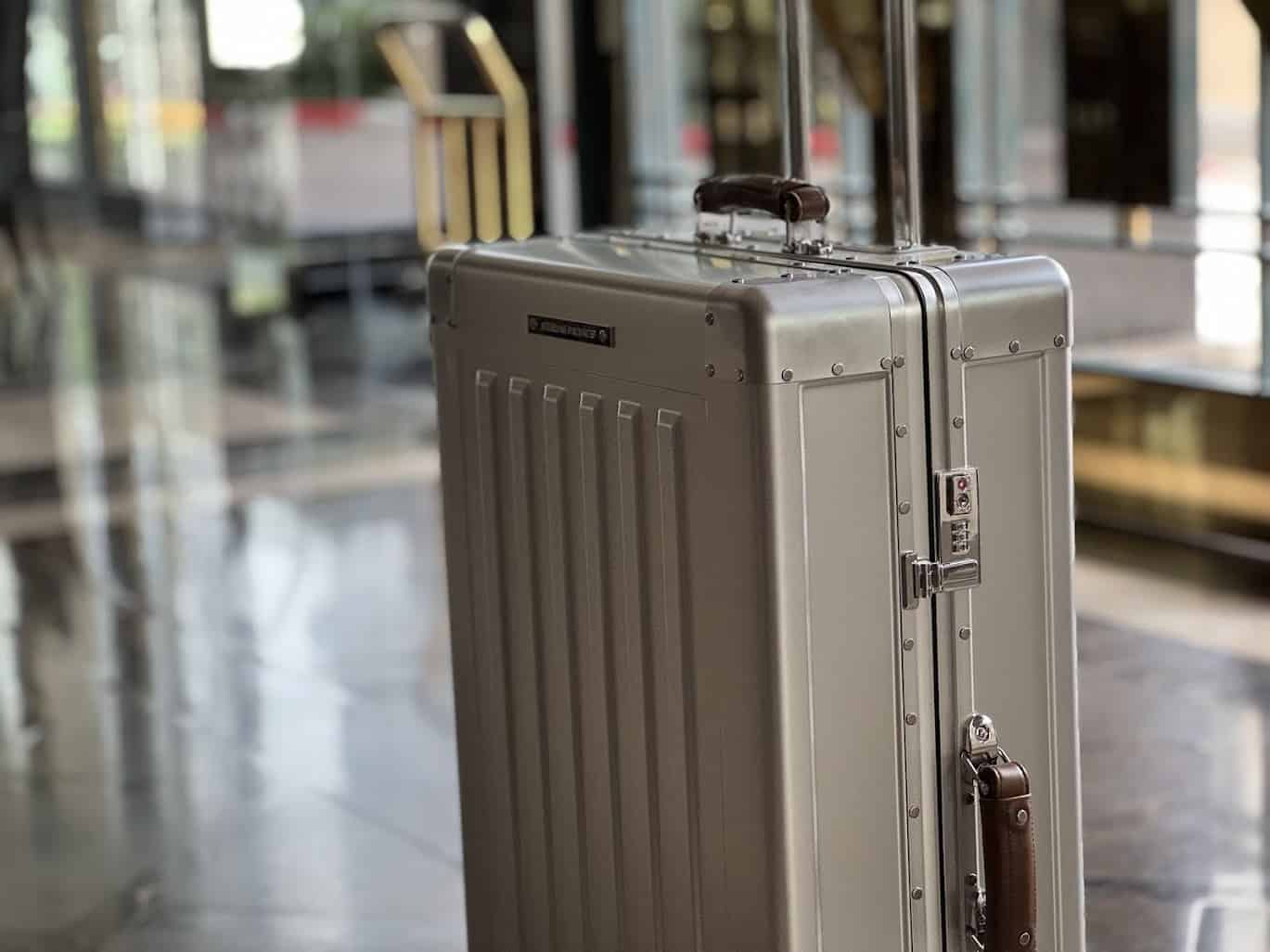 Close-up of Sterling Pacific suitcase showcasing its premium leather handle and riveted aluminum build in a polished hotel setting.