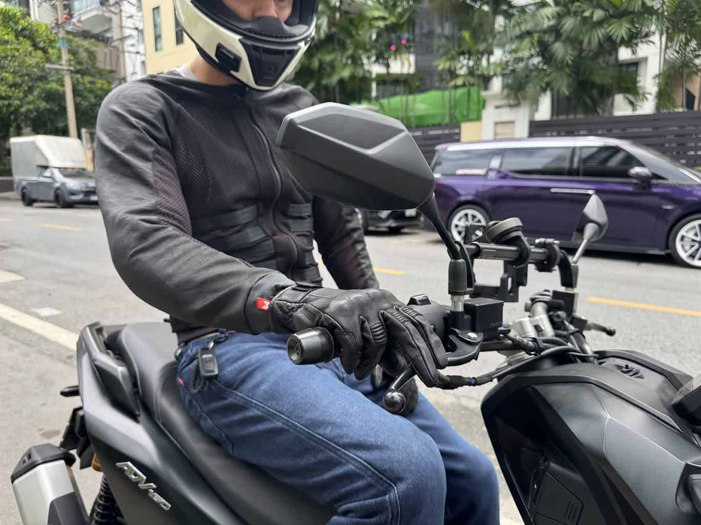 Motorcyclist wearing Pando Moto Arnie Slim jeans and Commando jacket on a black scooter in urban traffic
