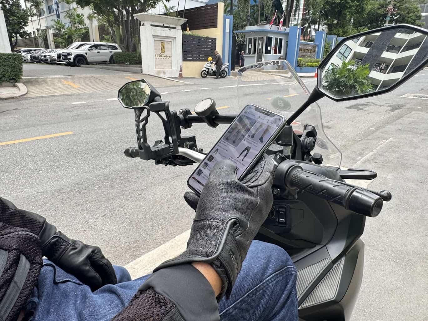 Rider using phone navigation while stopped on a city street in Bangkok