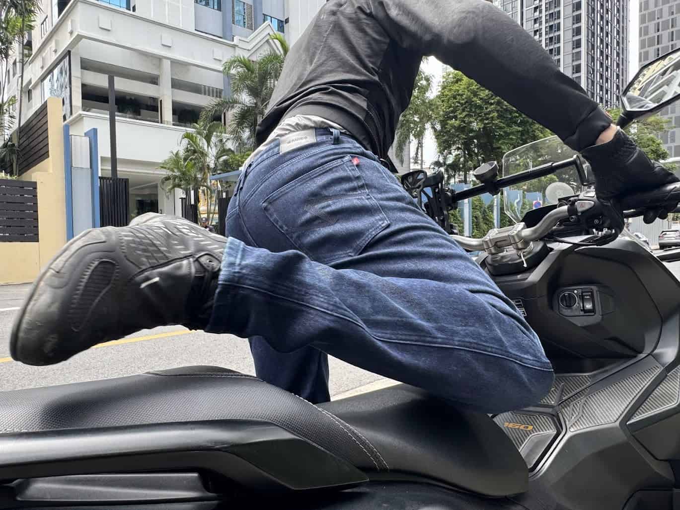 Close-up of rider swinging leg over scooter while wearing Pando Moto Arnie Slim jeans