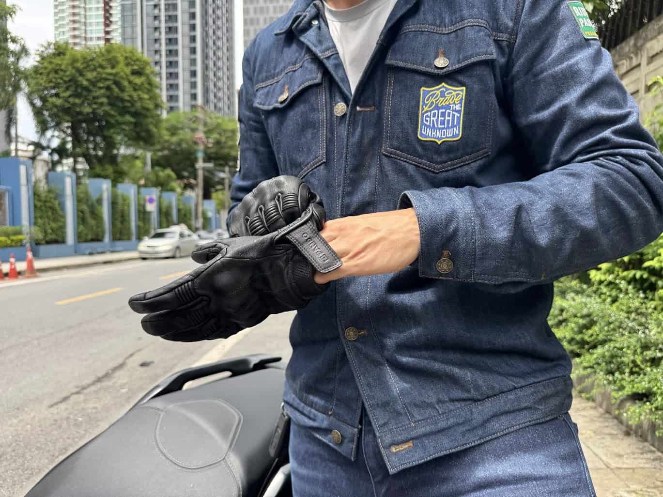 Rider adjusting gloves while wearing Pando Moto Arnie Slim jeans and Lusso leather motorcycle jacket