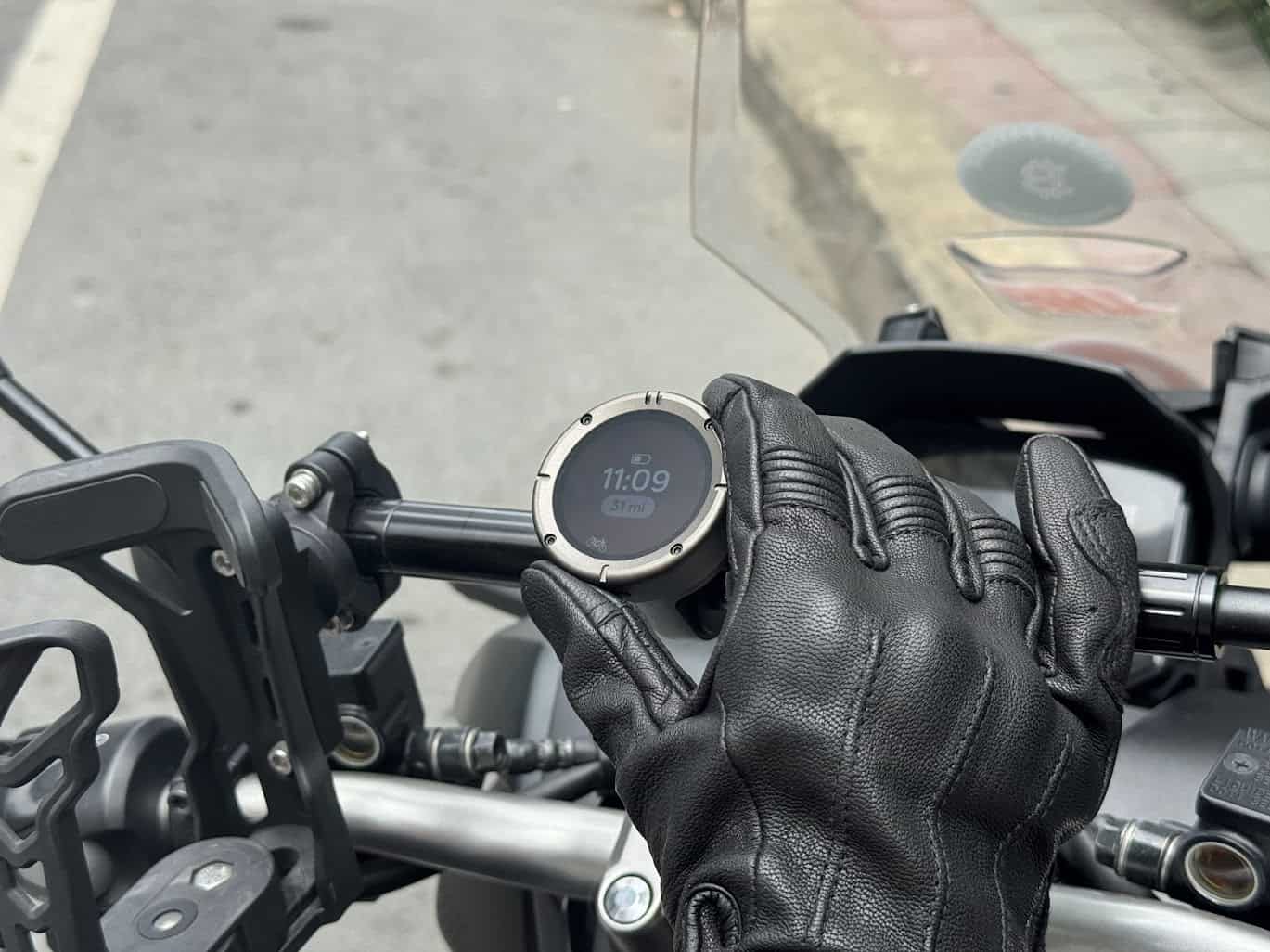 Beeline Moto II mounted on handlebars with glove-clad hand adjusting it