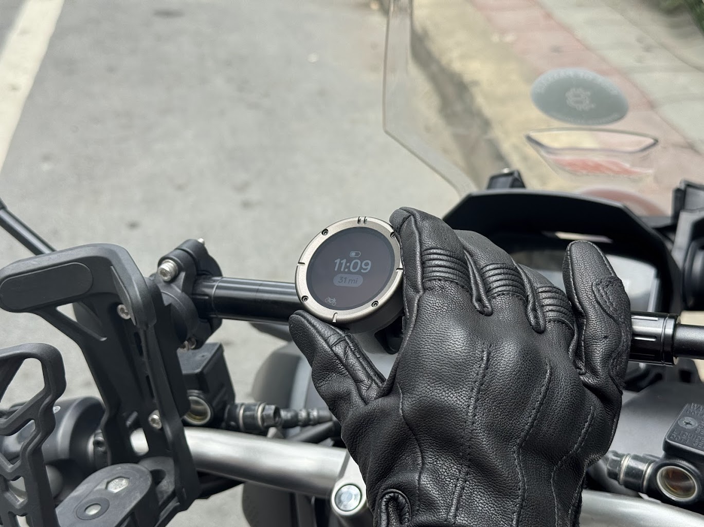 Gloved hand holding GPS on motorcycle handlebar