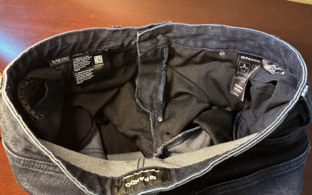 Interior view of Pando Moto Arnie Slim jeans showing CE tags, mesh liner, and armor pockets