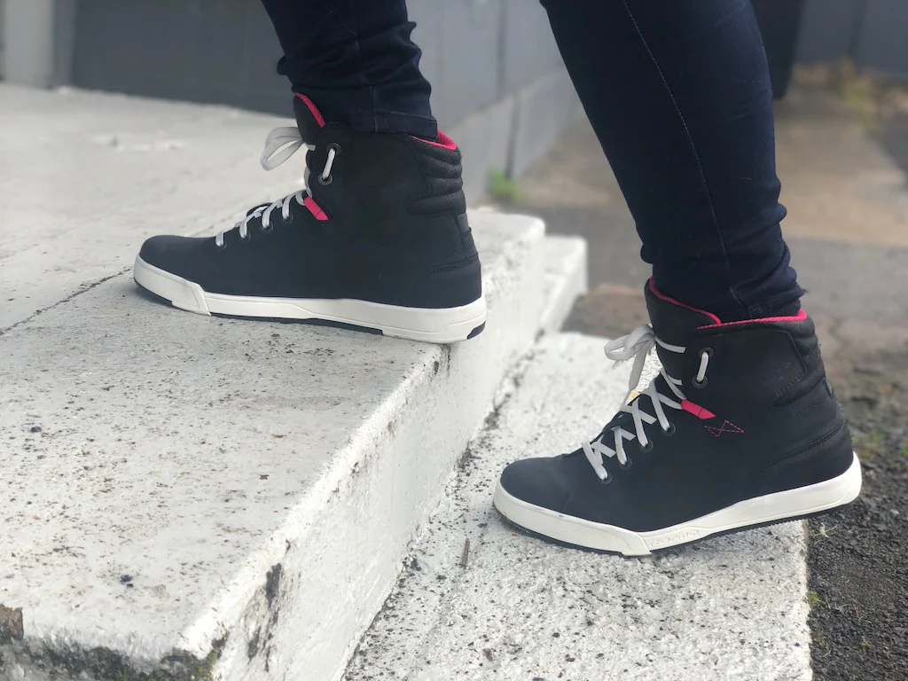 Forma Swift Dry Women’s motorcycle shoes worn on stairs, black with white soles and pink accents, styled like casual high-tops.