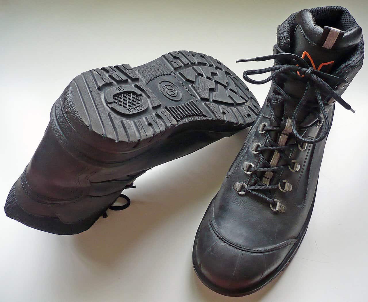 Black steel toe work boots shown from the top and sole view, highlighting thick tread and industrial-style lacing.