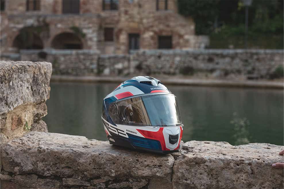 Schuberth S3 helmet in bold graphic colorway on a stone ledge near water