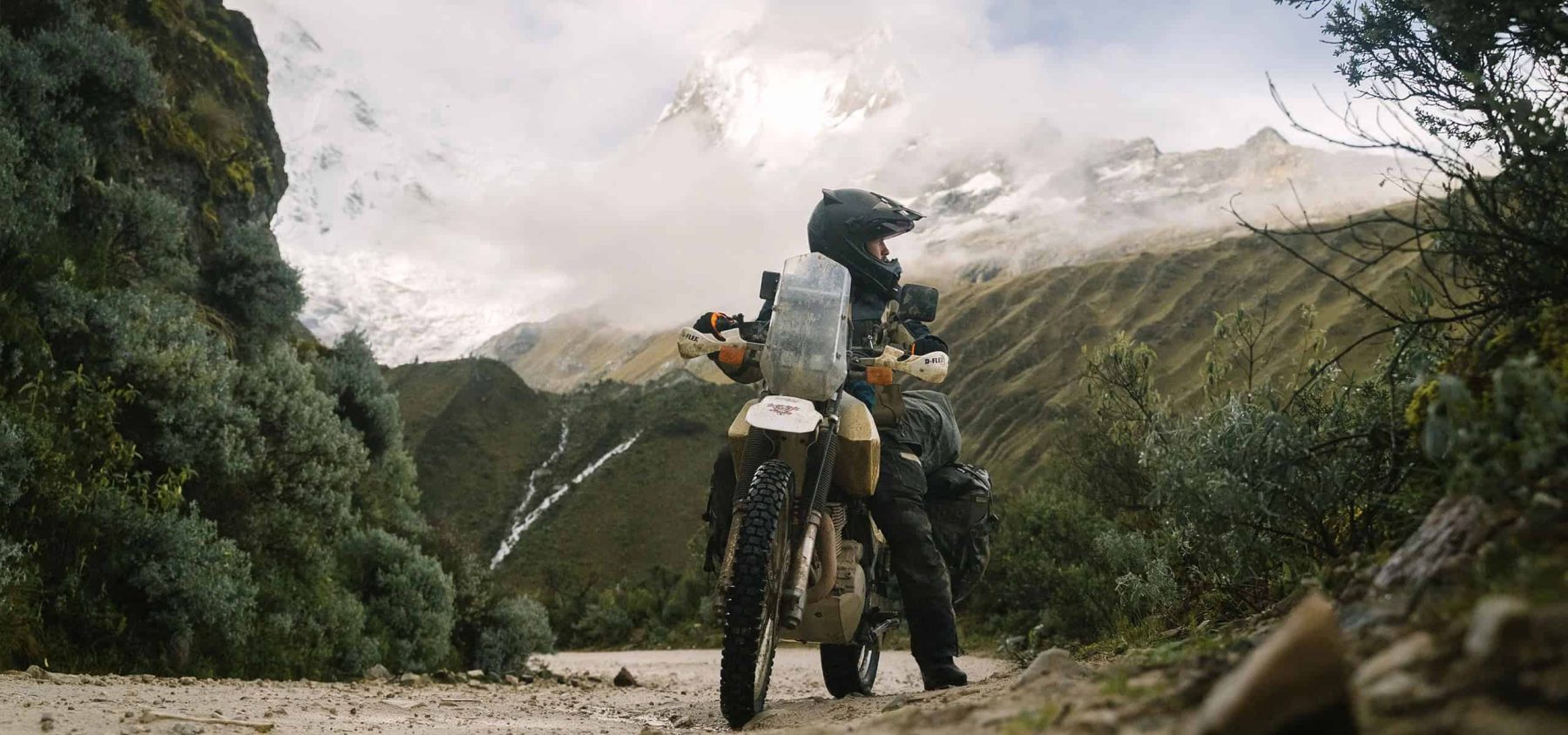 Adventure rider gripping bars in mountain storm with rugged gloves