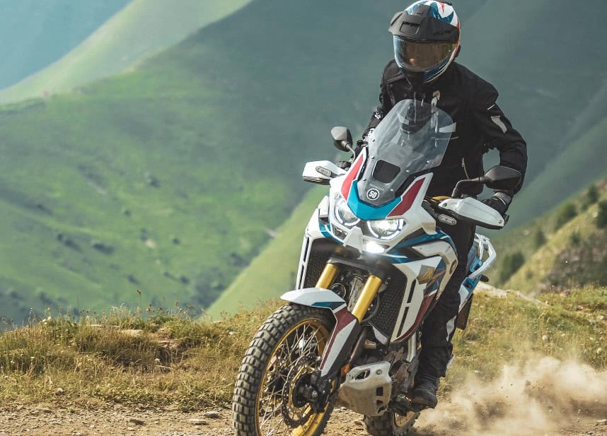 Adventure rider in full gear tackling a dirt trail with ADV helmet and dual-sport motorcycle