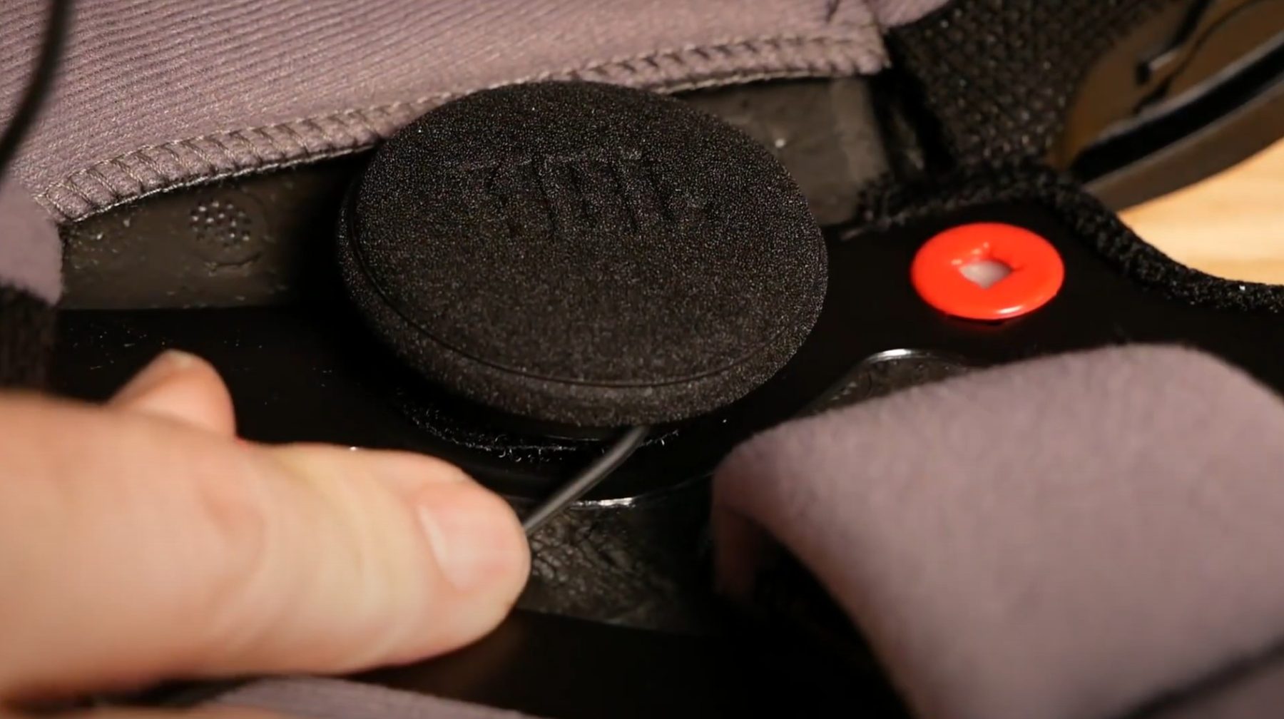 Close-up of a JBL helmet speaker being installed inside a motorcycle helmet with Velcro backing