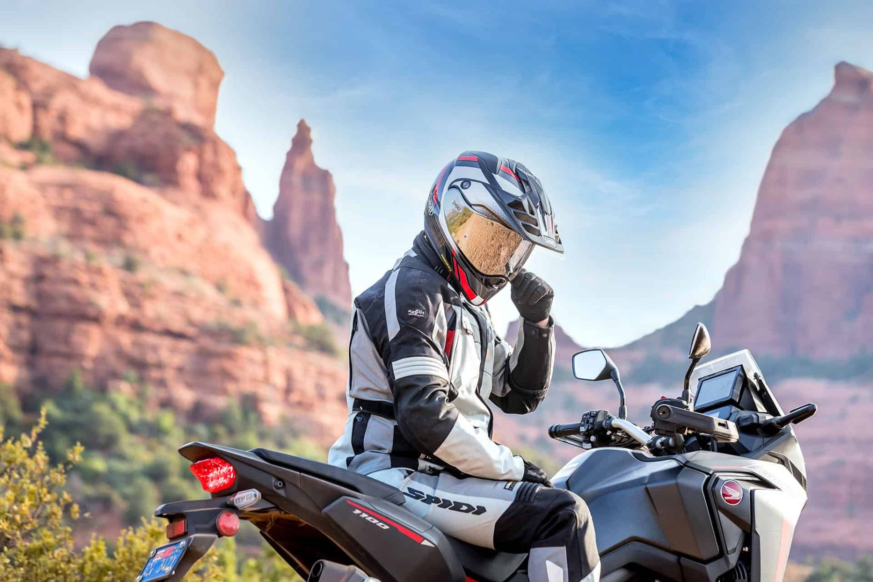 Rider wearing Shoei Hornet X2 helmet in desert canyon landscape on adventure motorcycle