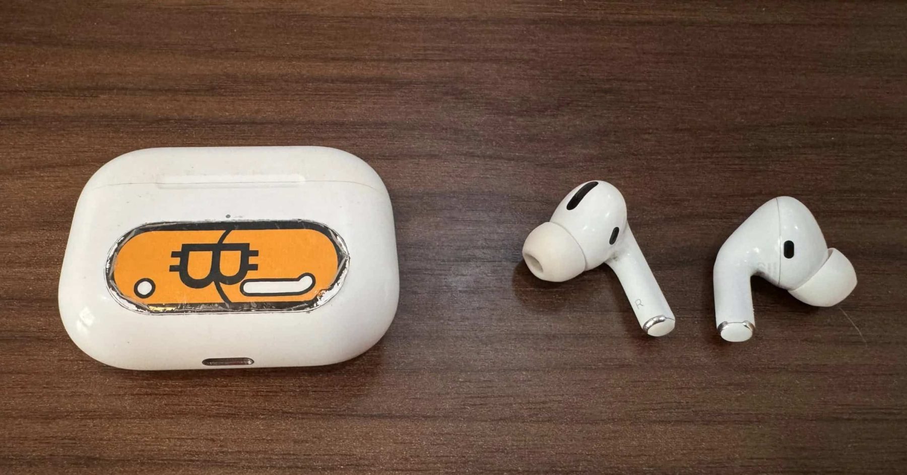 Apple AirPods on a wooden table with custom case sticker
